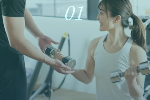 ジムでトレーナーのサポートを受けて筋トレを行う女性