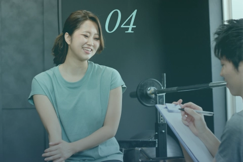 ジムで女性がトレーナーとカウンセリングを受ける様子